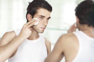 Man looking at his reflection; using facial toner